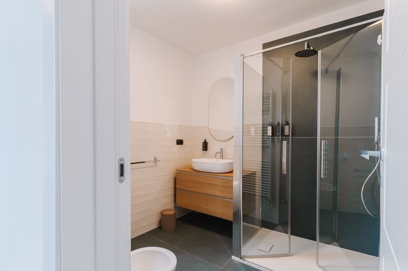 Bagno con doccia in cristallo e mobile in legno