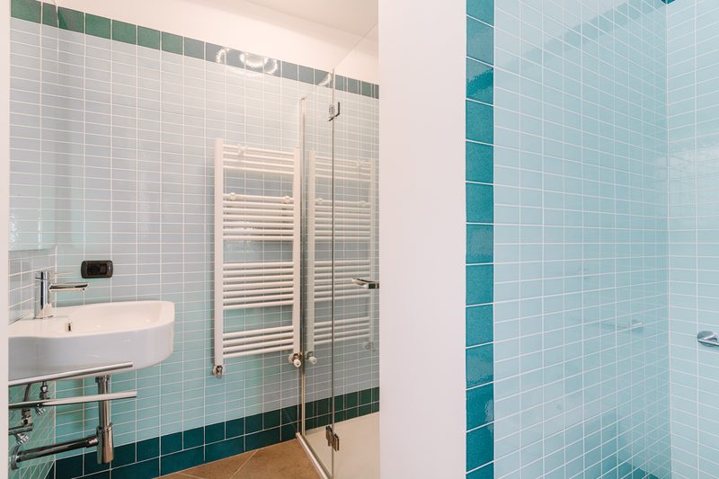 Bagno con rivestimento in maioliche verdi e doccia