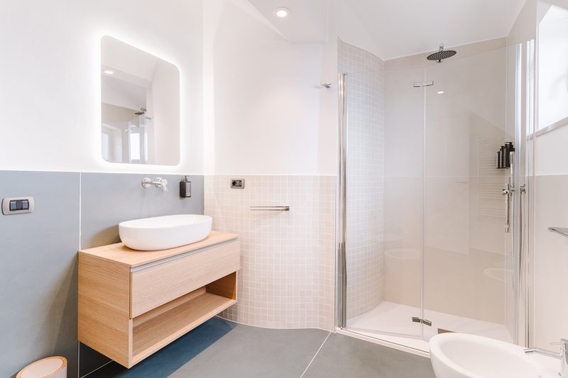 Bagno luminoso con mobile in legno e doccia walk-in