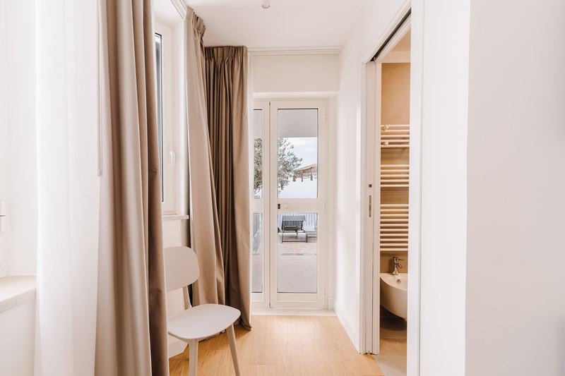 Angolo della camera con accesso al bagno en suite e tende in lino