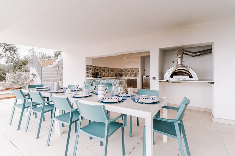 Cucina esterna con forno a legna e lungo tavolo da pranzo