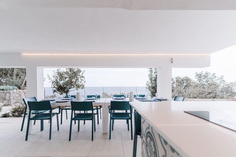 Cucina esterna coperta con tavolo e vista sugli ulivi