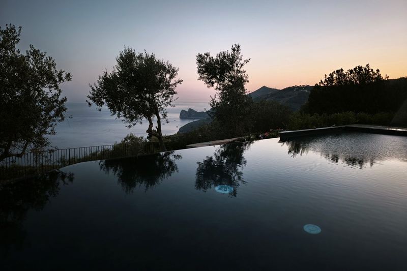 Piscina a sfioro al tramonto con riflessi degli ulivi sull'acqua