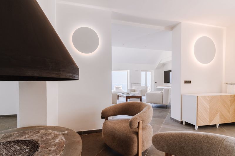 Zona lounge con poltrone e camino, aperta sul salone principale