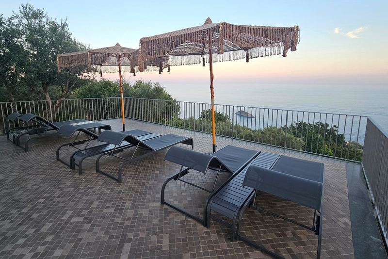 Lettini prendisole e ombrelloni in macramè sulla terrazza vista mare
